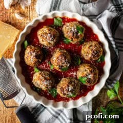 Close-up of a bowl of cooked, juicy meatballs, garnished with fresh herbs.