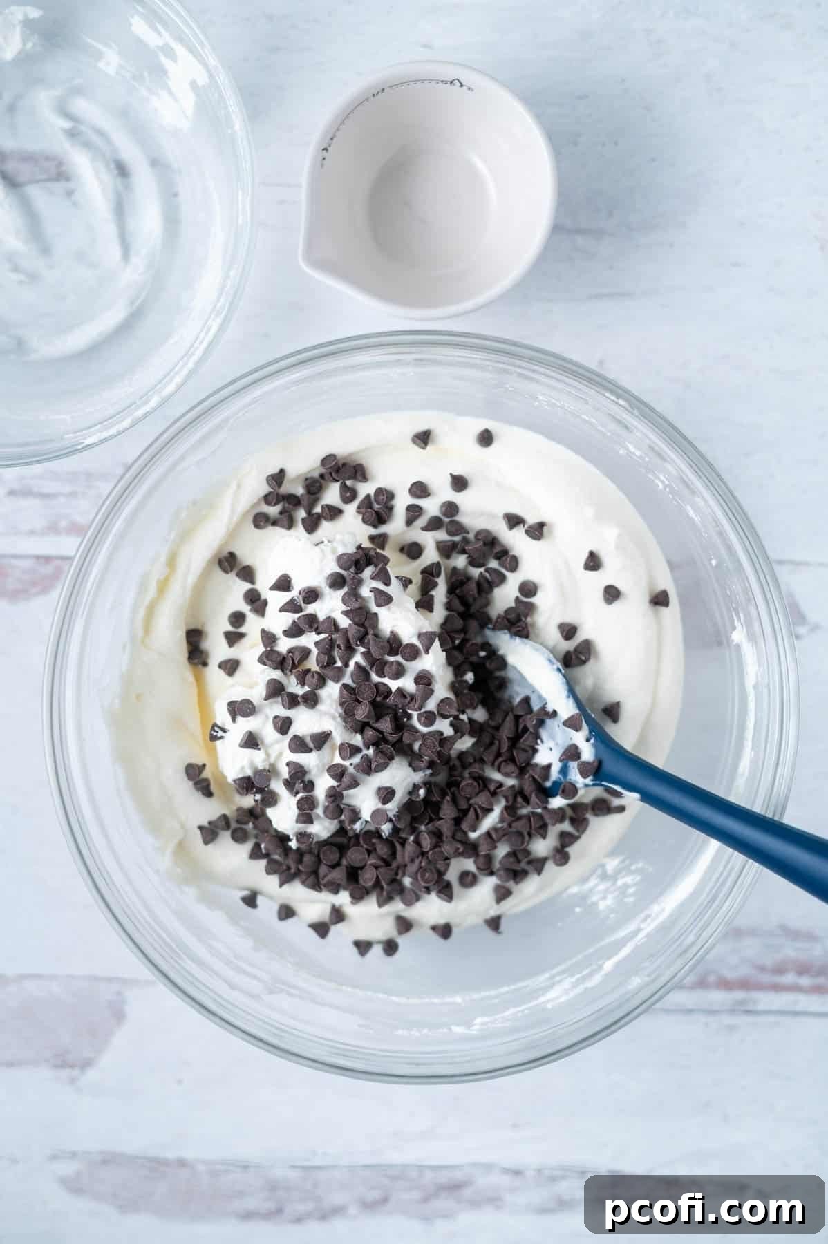mini chocolate chips sprinkled over cannoli dip in a bowl with a spatula