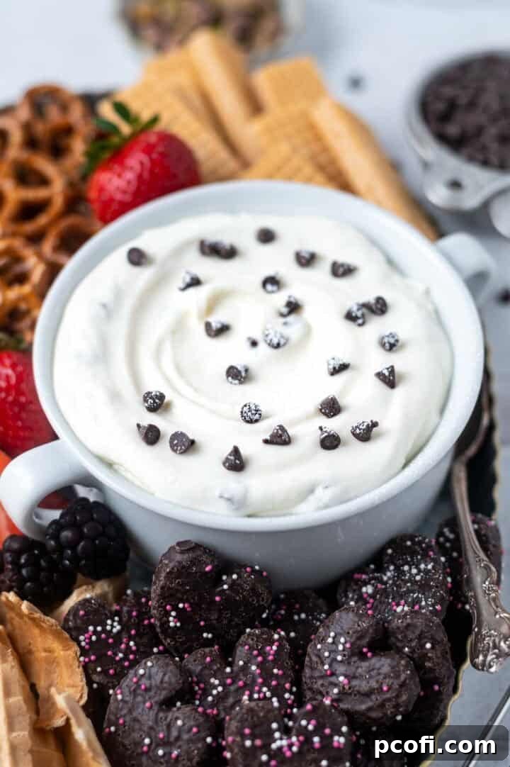 cannoli dip in a bowl with powdered sugar and mini chocolate chips on top.