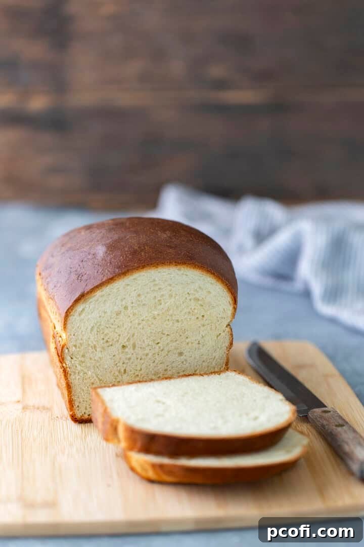 Perfectly baked milk bread loaf on a wooden cutting board, ready to be sliced.