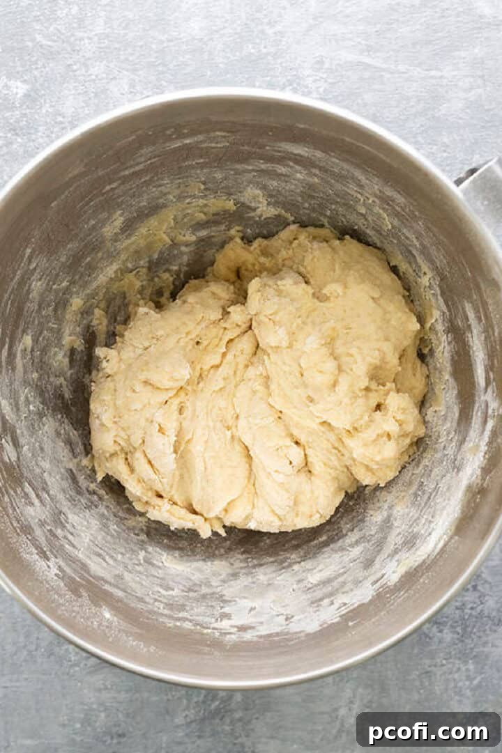 Adding warm milk, melted butter, and lightly beaten egg to the dry ingredients in a mixer.