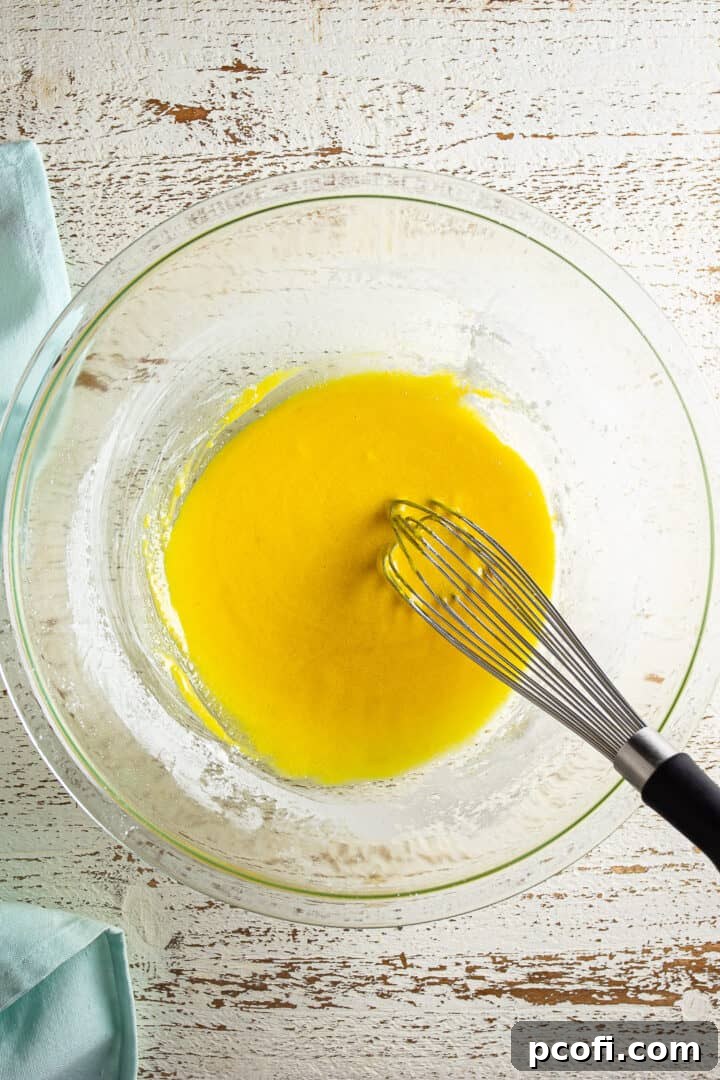 Egg yolks being whisked into dry ingredients until smooth.