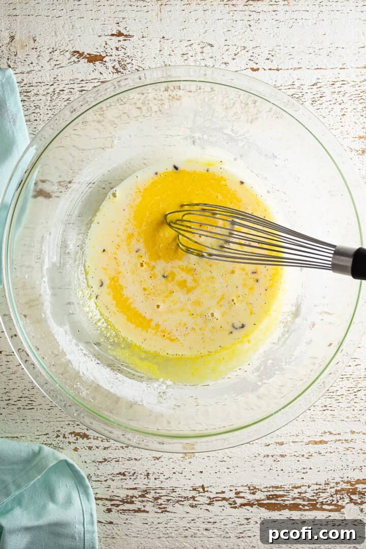Hot milk being slowly whisked into the egg yolk mixture.