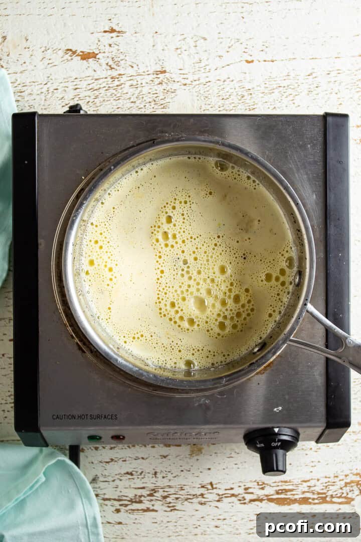 Pastry cream mixture cooking in a pot, being constantly whisked.