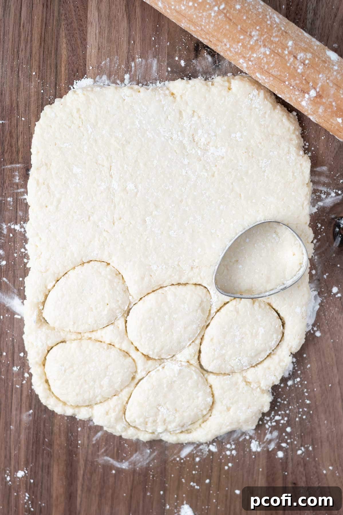coconut filling on a cutting board being cut into egg shapes with a cookie cutter