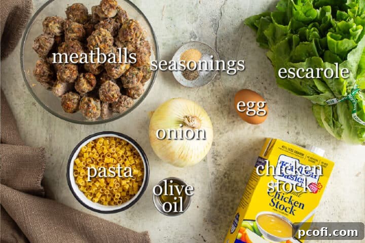 All the fresh ingredients laid out on a kitchen counter, ready for making Italian wedding soup. Includes ground meat, ricotta, onion, eggs, broth, escarole, and small pasta.