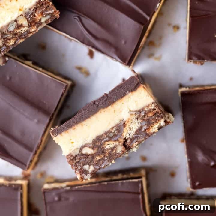 Close-up of a three-layered no-bake Nanaimo bar, showcasing its distinct chocolate coconut base, creamy custard, and glossy ganache top.