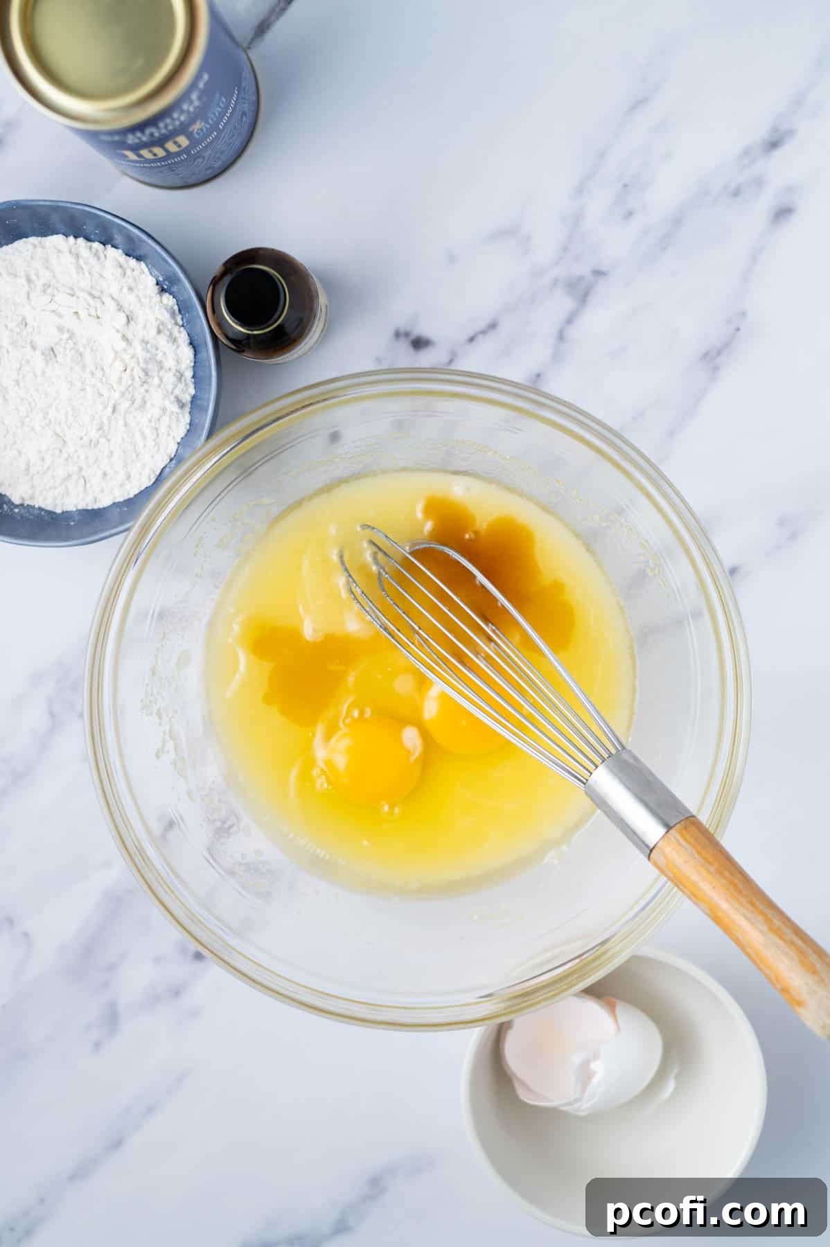 Step 2: Eggs and pure vanilla extract are added to the whisked butter and sugar mixture in a bowl, ready to be combined.