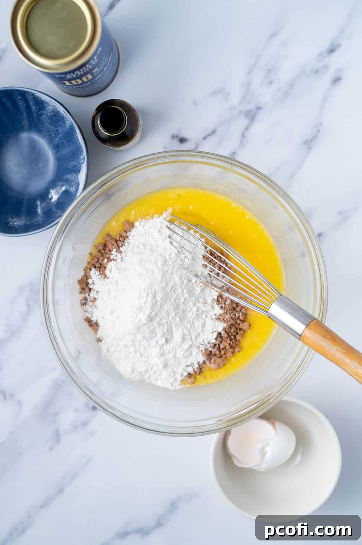 Step 3: Melted butter and sugar whisked in a bowl, with cocoa powder and flour added on top of the wet ingredients, ready for final mixing.