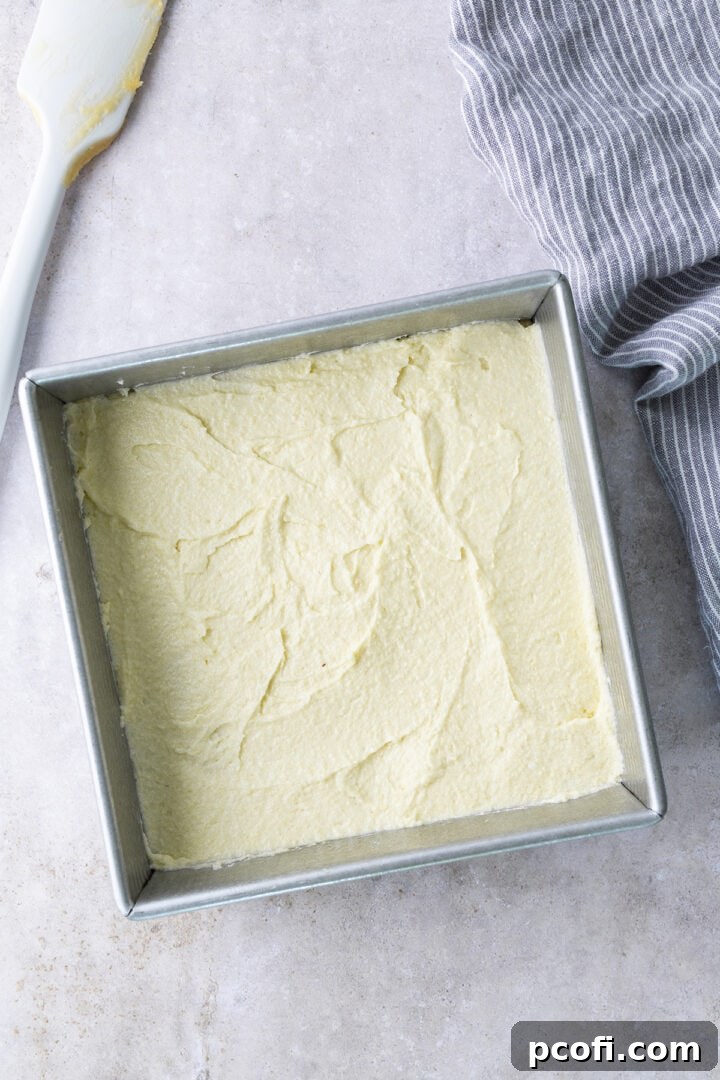 Frangipane filling being spread evenly over the blondie batter in the pan