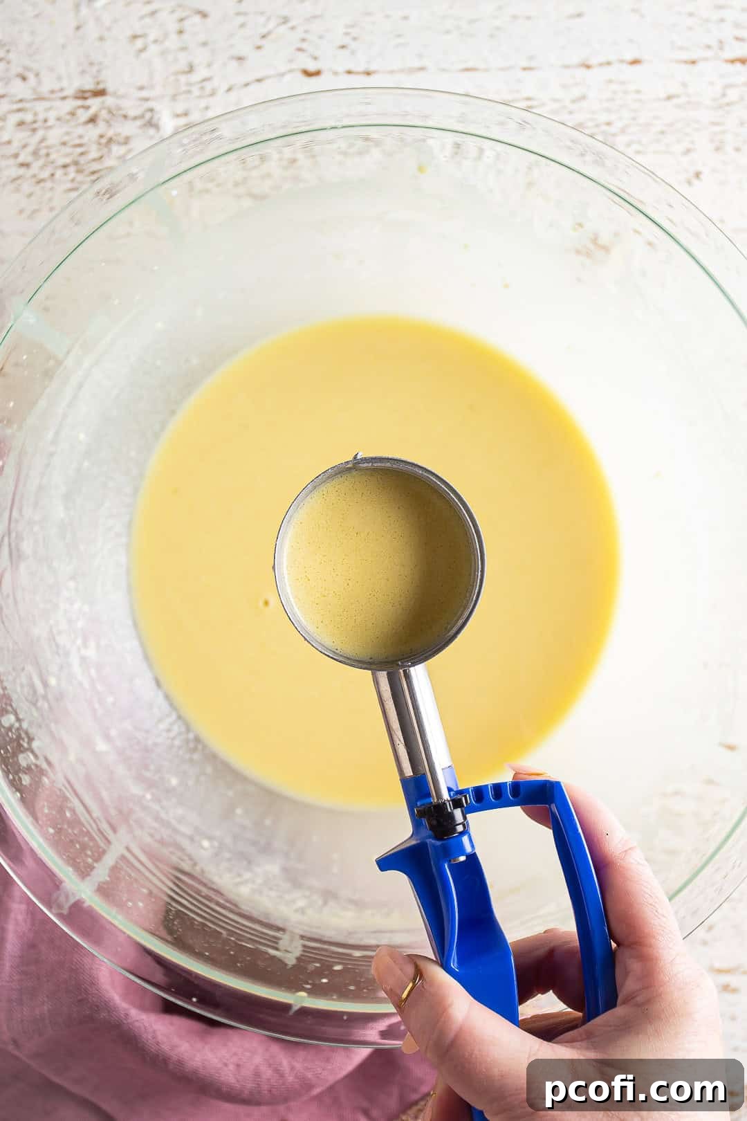 Scooping crepe batter with an ice cream scoop.