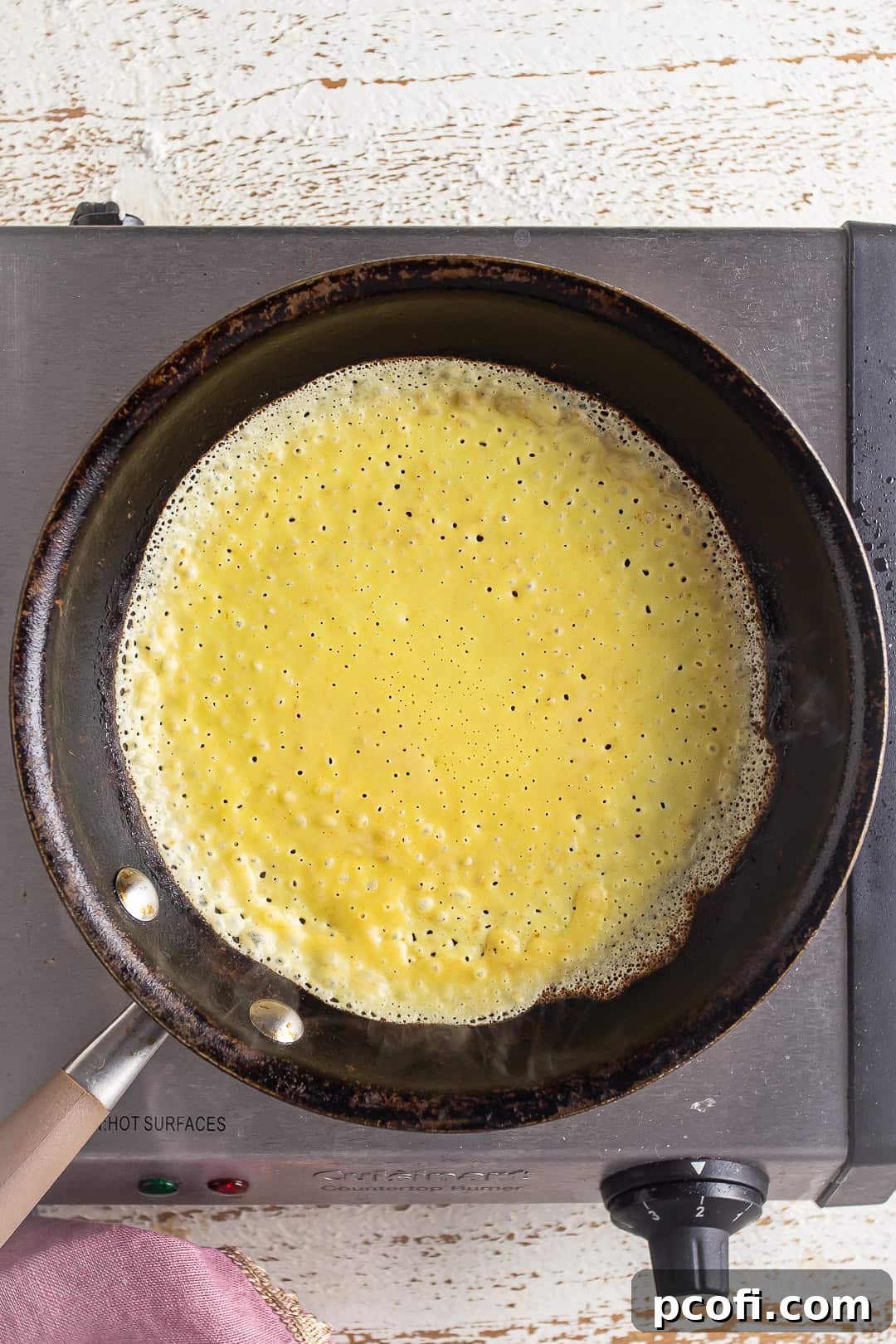 Cooking crepe batter in a small skillet on the stovetop.