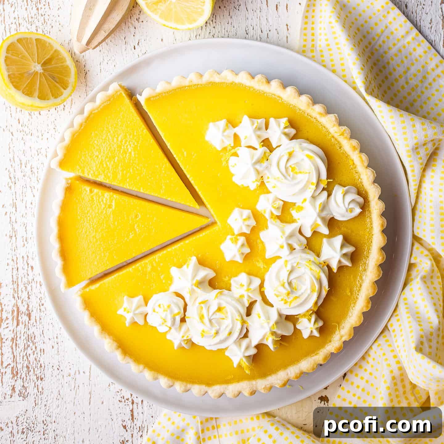 Overhead image of a sliced lemon tart with whipped cream rosettes.