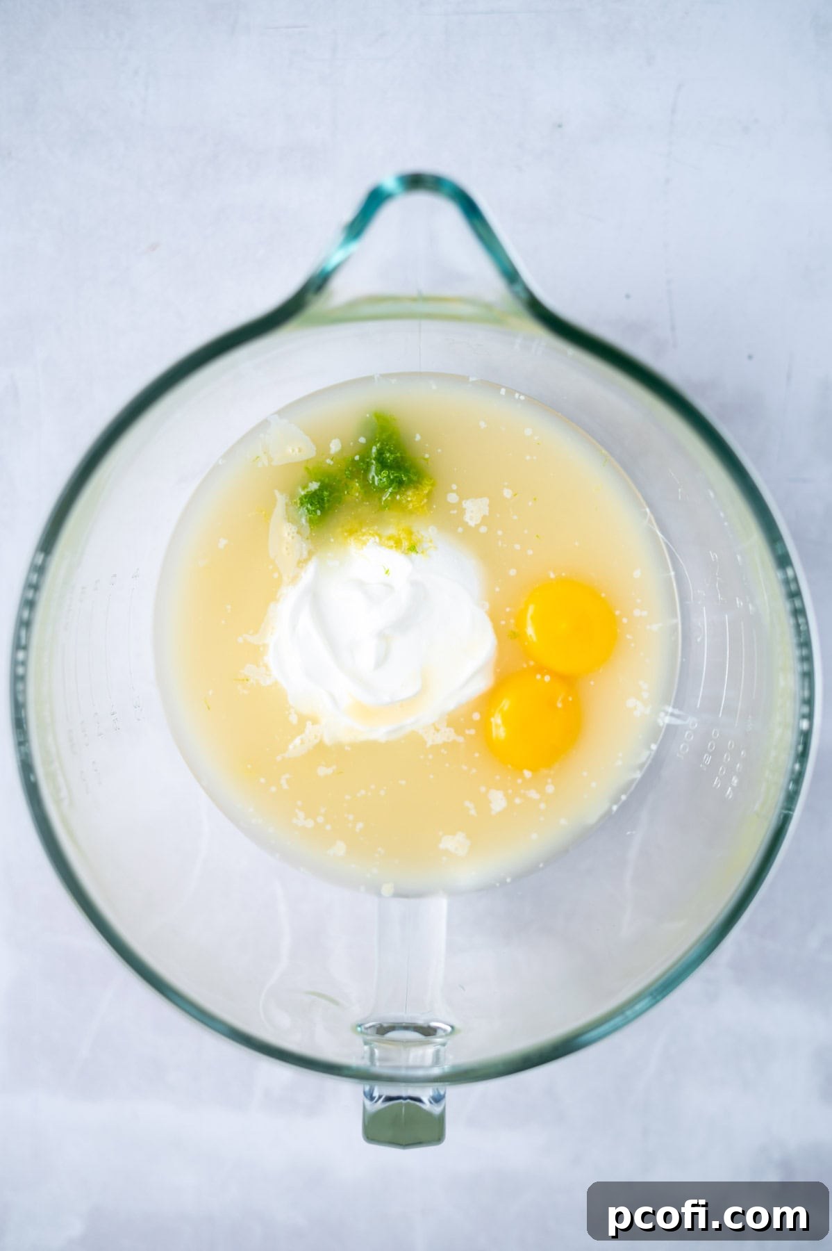 Mixing bowl with sweetened condensed milk, fresh lemon and lime juice, sour cream, citrus zest, and egg yolks for the pie filling.