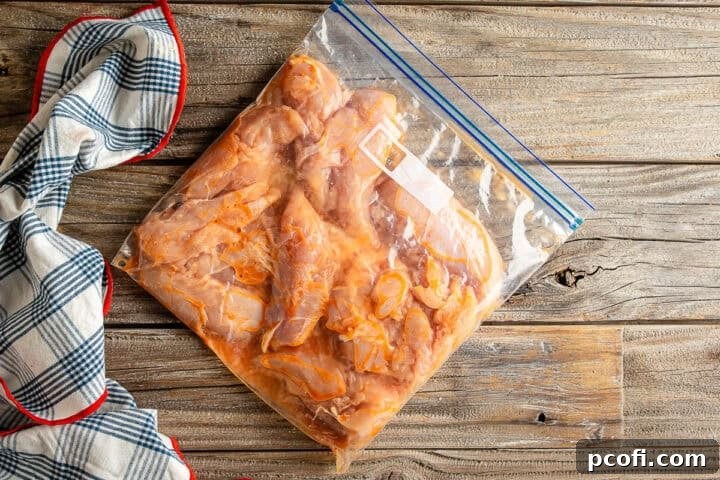 Chicken tenders submerged in a flavorful brine of hot sauce, water, and salt, marinating for tenderness.