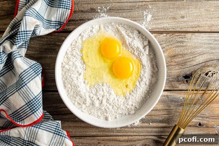Adding two large eggs to a bowl of seasoned flour, the first step in creating the batter.