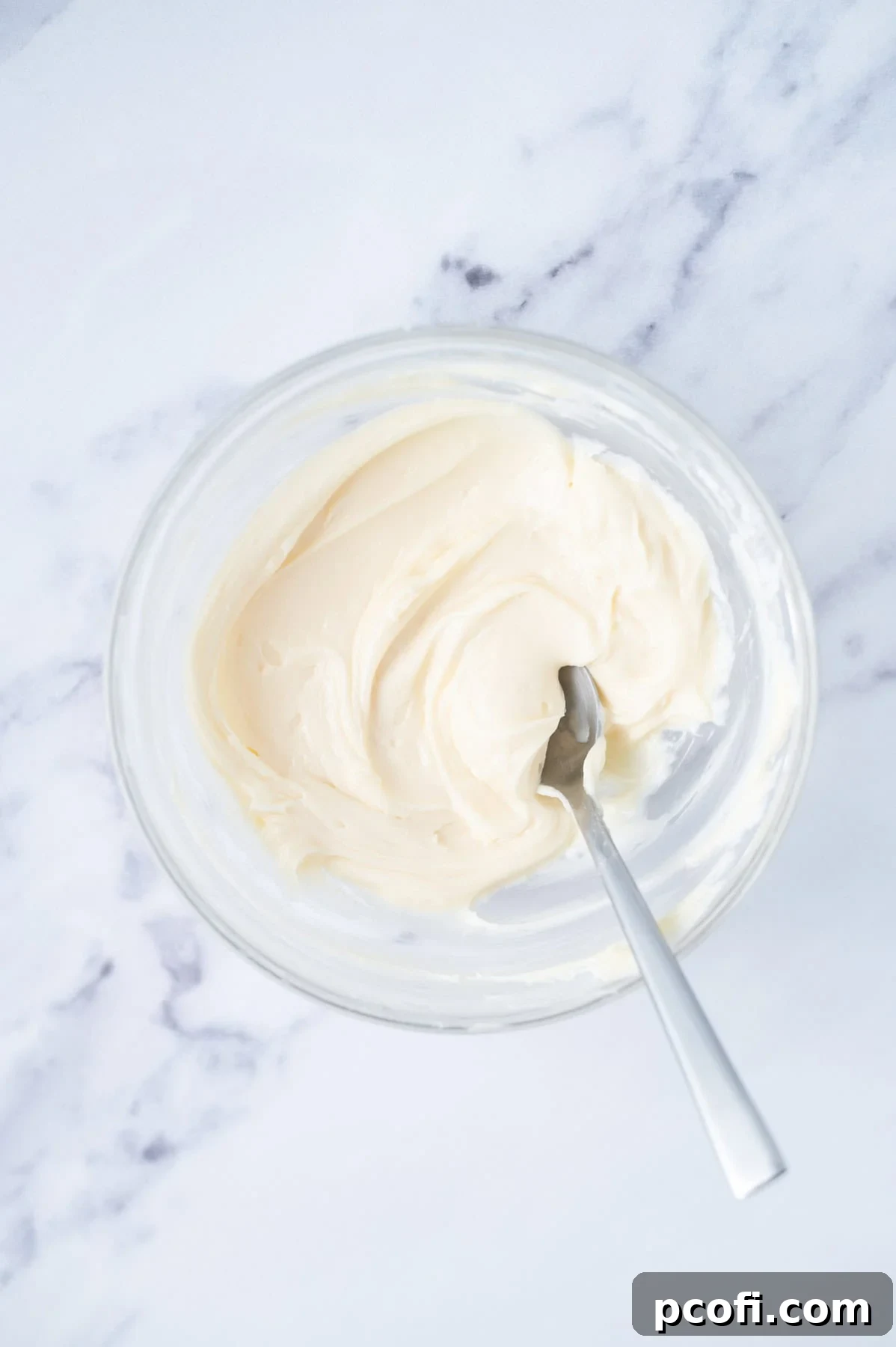 Cream cheese filling in a mixing bowl with a spoon