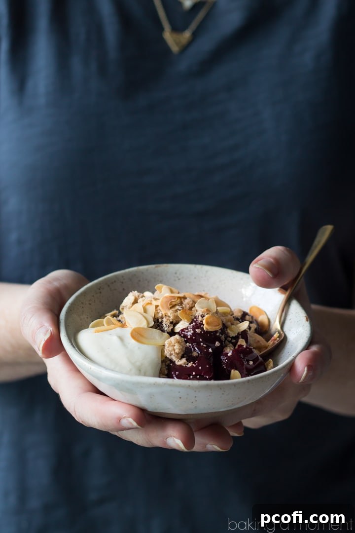A beautifully presented serving of no-bake cherry crumble, highlighting the layers of cherry, streusel, and a generous dollop of vanilla Greek yogurt.