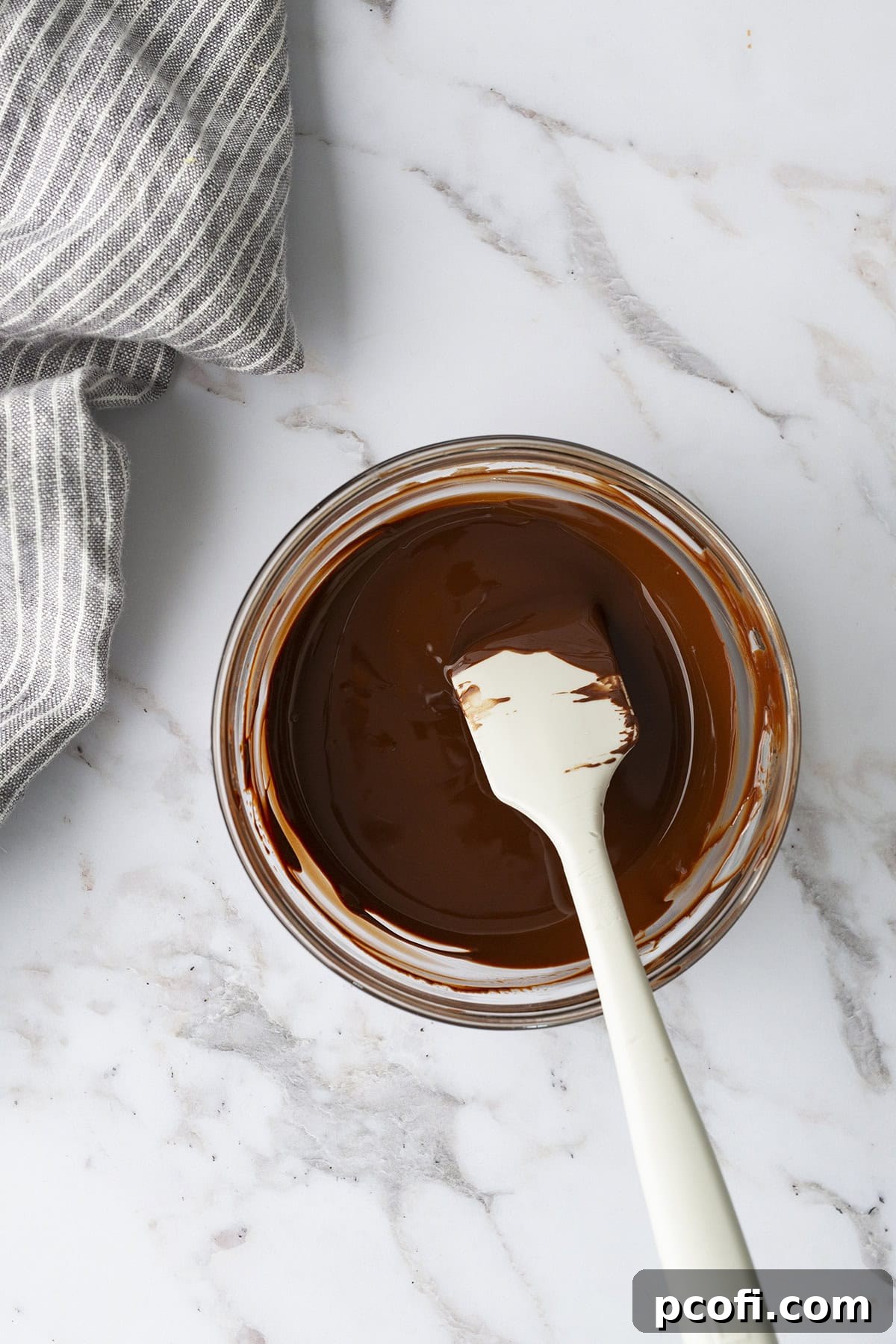 Smooth, melted bittersweet chocolate in a microwave-safe bowl, ready for cooling and incorporation into the frosting.