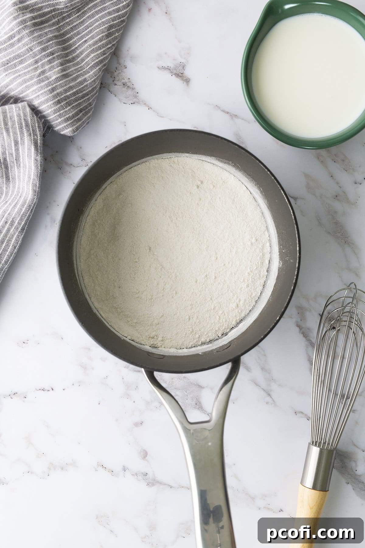 Granulated sugar and all-purpose flour whisked together in a medium saucepan, ready for liquid.