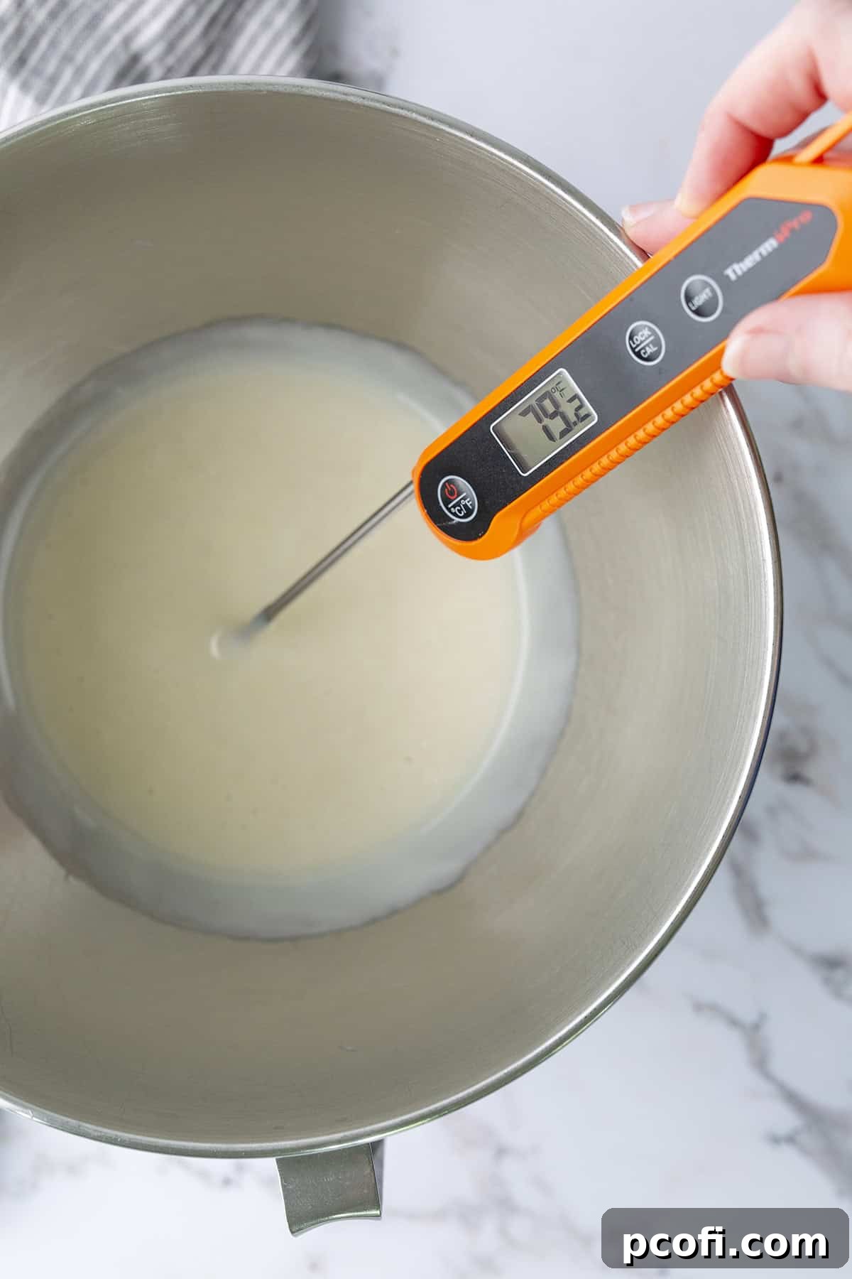 A digital thermometer inserted into the cooked flour mixture in a stand mixer bowl, showing the cooling process.