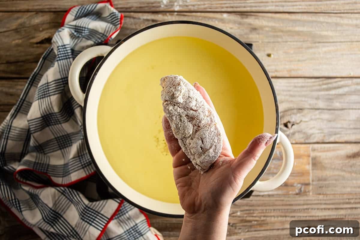 Carefully placing breaded chicken tenders into hot oil for frying, creating a sizzle.