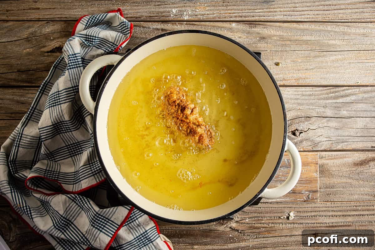 Homemade chicken fingers frying in hot oil until they turn golden brown and perfectly crisp.
