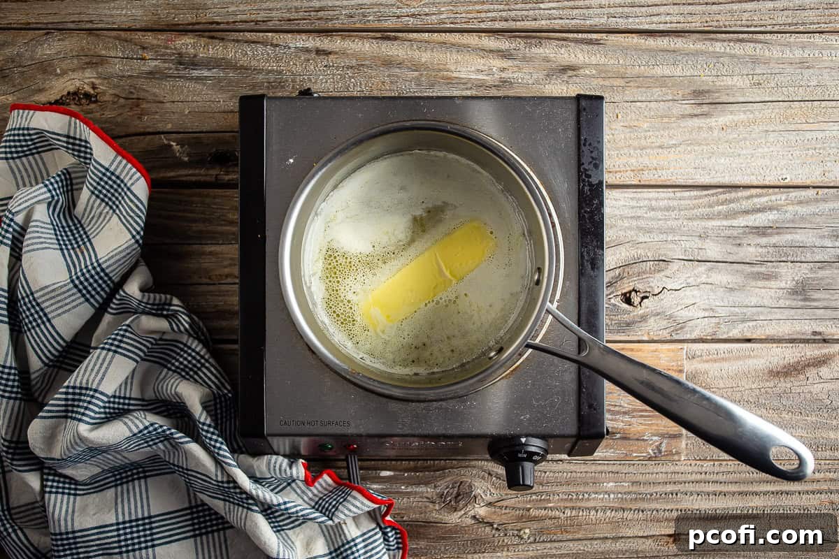 Unsalted butter melting in a small pot over low heat.