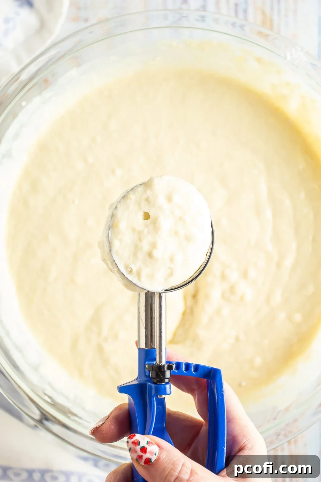 Scooping homemade waffle batter into a measuring cup, ready for the waffle iron.