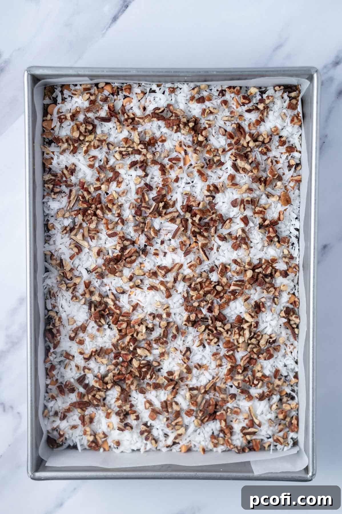 chopped pecans layered over coconut in a baking pan