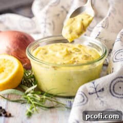 Finished Béarnaise sauce in a glass dish with a spoon inside.