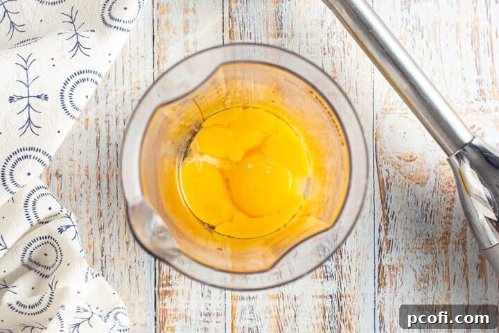 Egg yolks in a mixing container for homemade béarnaise sauce, before being blended with a stick blender.