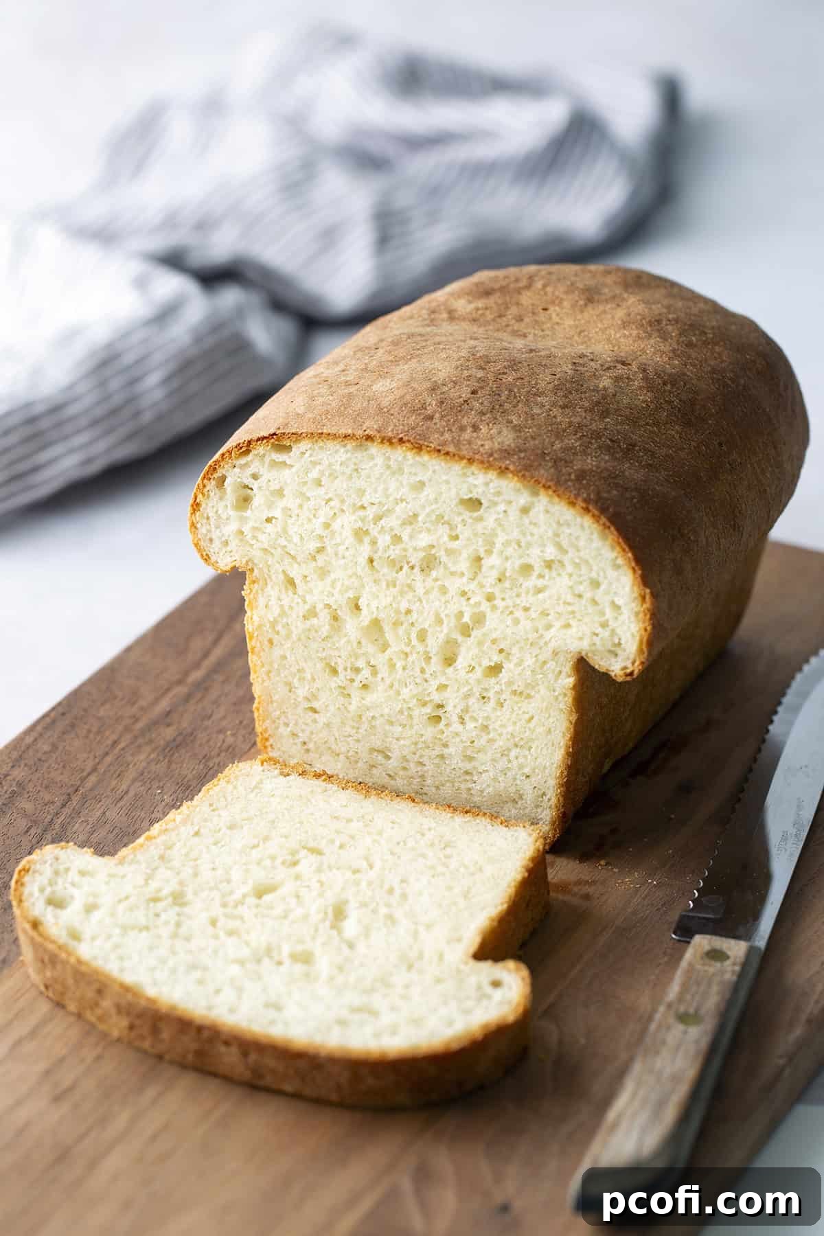 Freshly baked Homemade Potato Bread on a rustic cutting board with a bread knife, ready to be sliced and enjoyed.