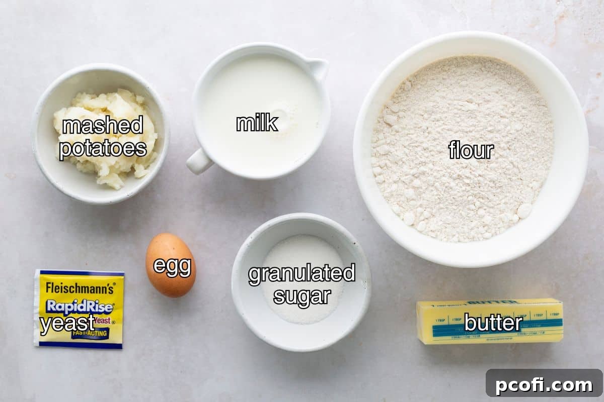 All the necessary ingredients for Homemade Potato Bread laid out on a kitchen counter, including flour, sugar, yeast, salt, butter, mashed potatoes, milk, and an egg.