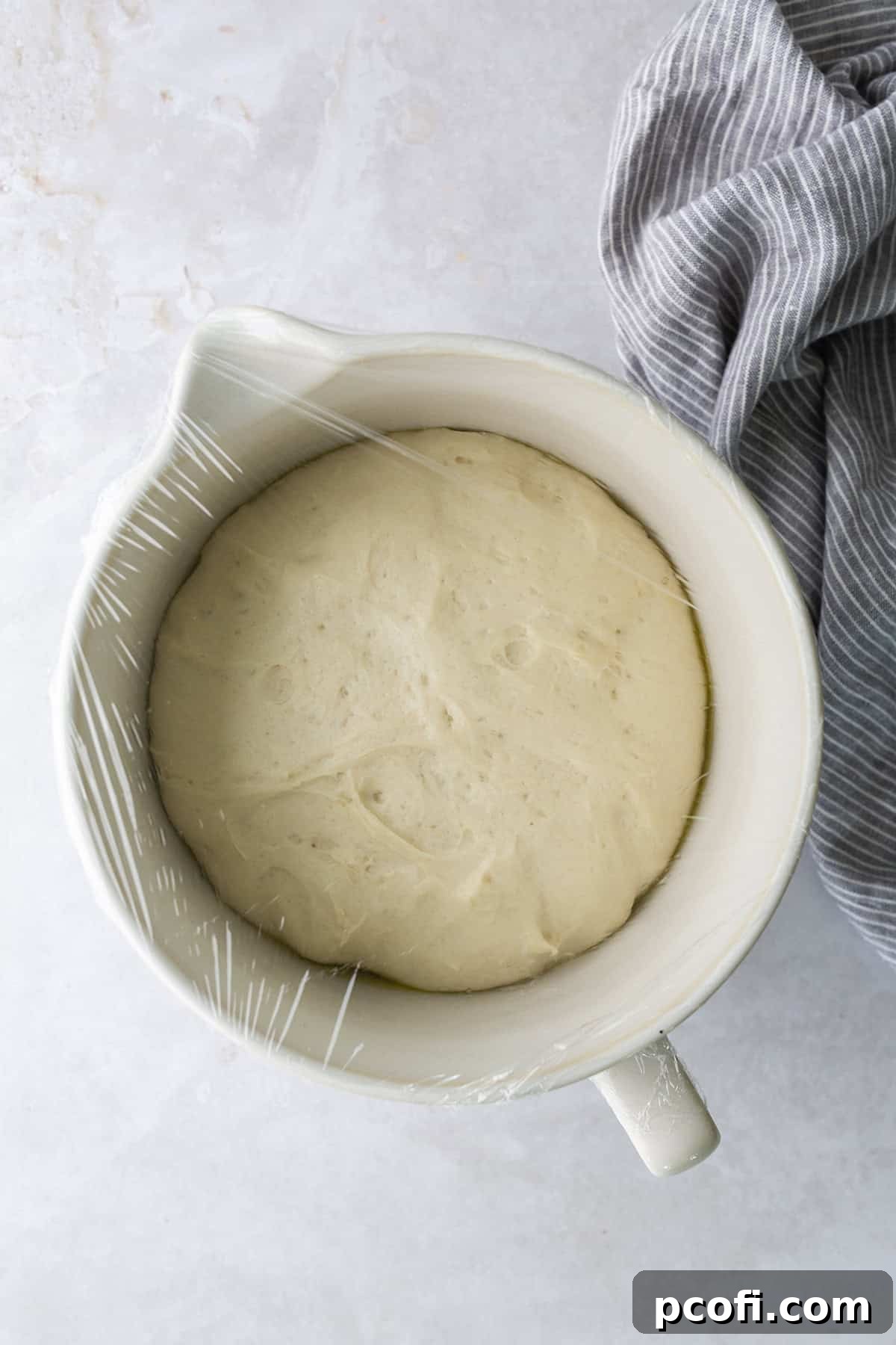 Potato bread dough in a bowl, having successfully doubled in size after its first proofing, indicating it's ready for the next step.