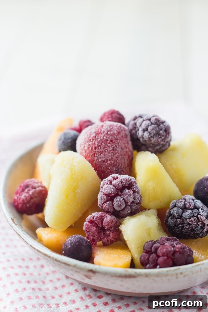 A variety of frozen fruits including peaches, pineapple, and mixed berries, ready for blending into a sangria slushie.
