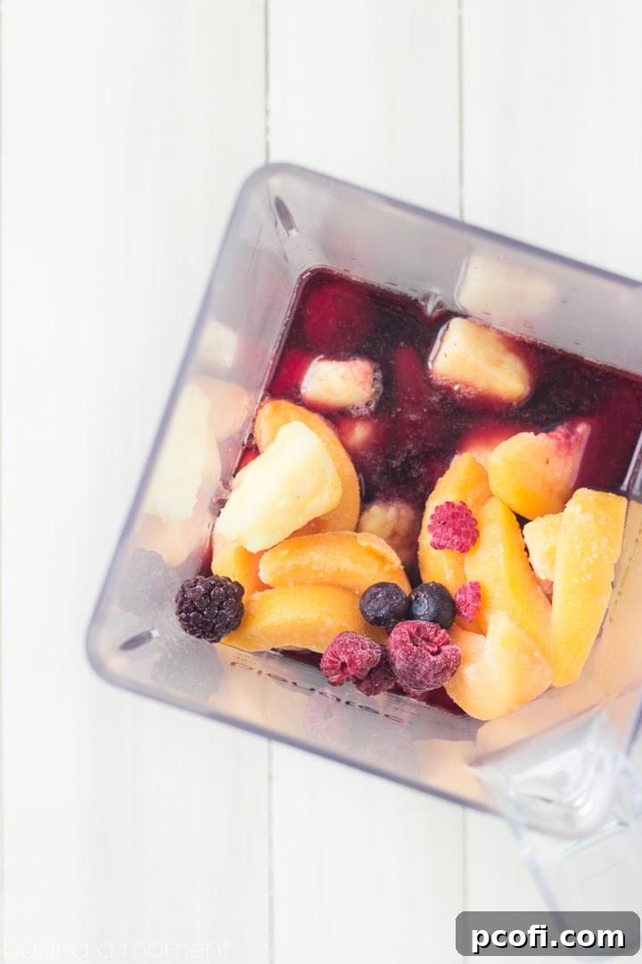 A vibrant red Frozen Sangria Slushie garnished with fresh orange slices and a sprig of mint, ready to be enjoyed.