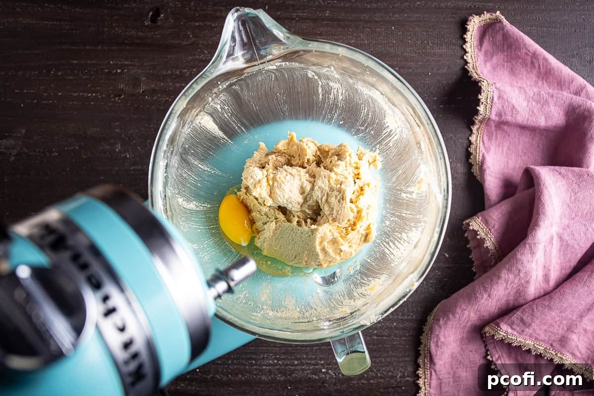 Eggs being added to the cookie dough before being mixed.