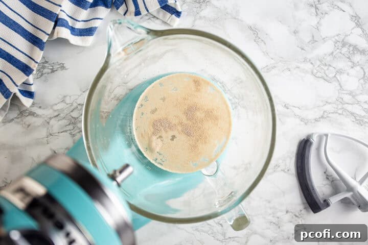 A bowl of rising pizza dough covered with plastic wrap.