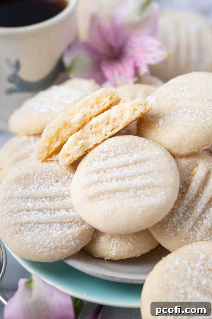 A selection of melting moments cookies beautifully presented on a plate, with one cookie thoughtfully broken in half to reveal its invitingly soft and crumbly texture.