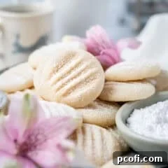 A beautiful pile of melting moments cookies on a plate, surrounded by fresh flowers, ready to be enjoyed.