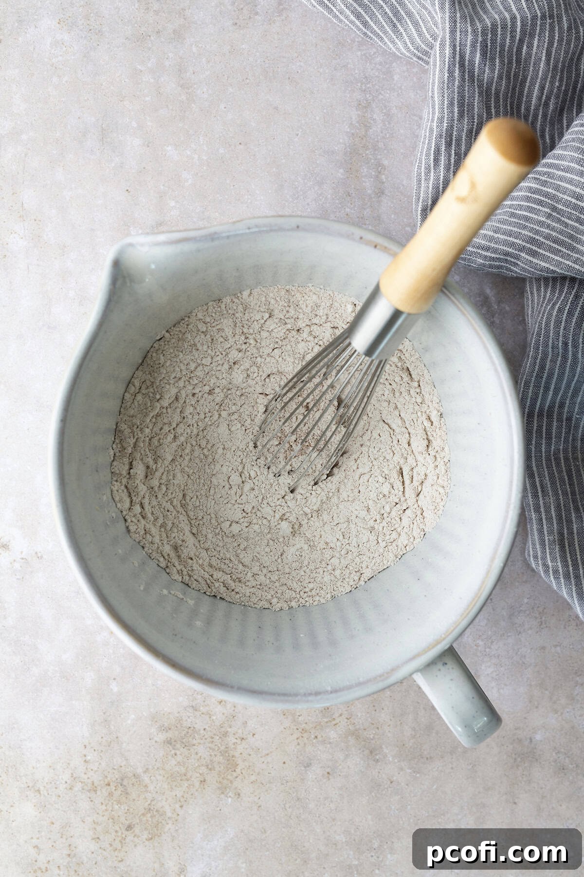 Dry ingredients for zucchini cake (flour, baking soda, baking powder, salt, cinnamon) being whisked in a bowl.