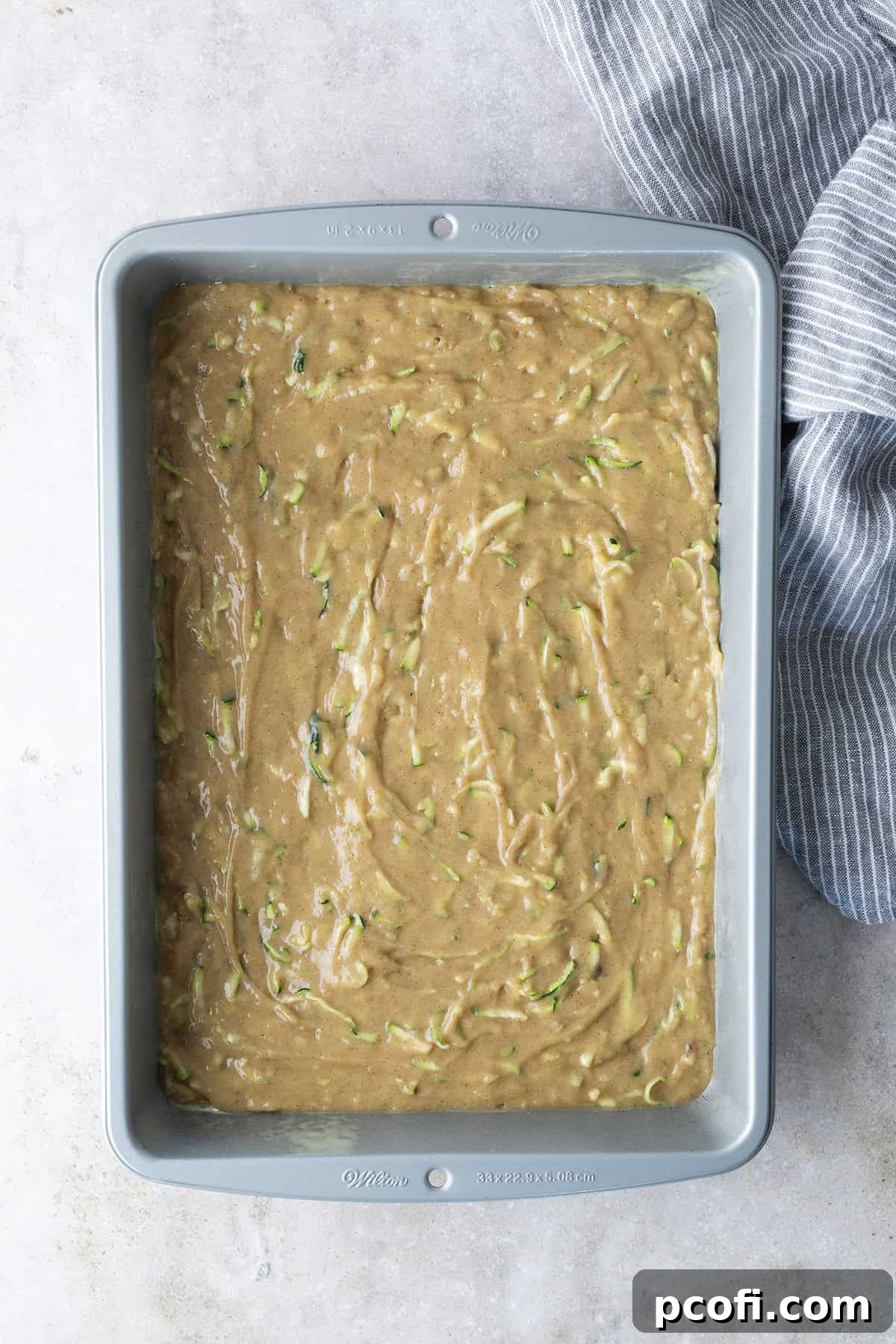 Unbaked zucchini cake batter neatly poured into a rectangular baking pan, ready for the oven.