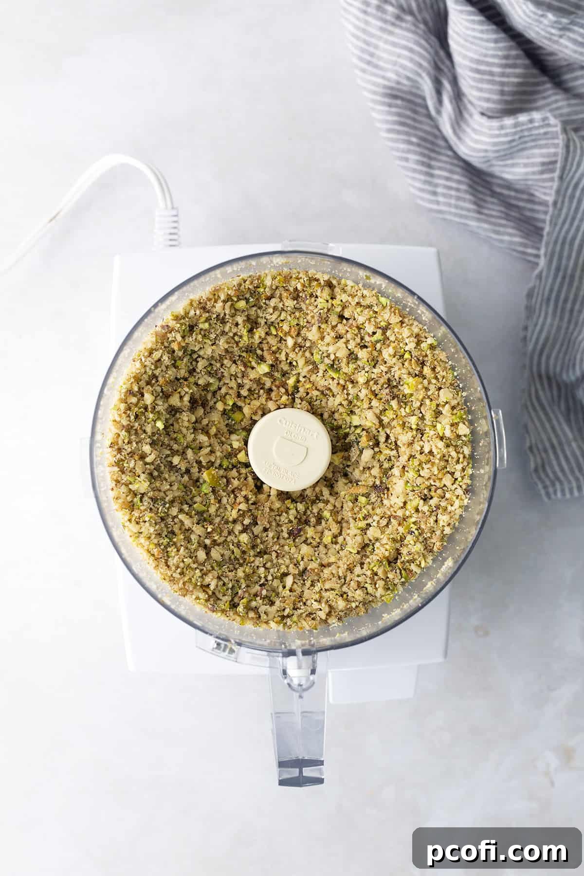 Finely chopped walnuts and pistachios in a food processor bowl, ready for seasoning.