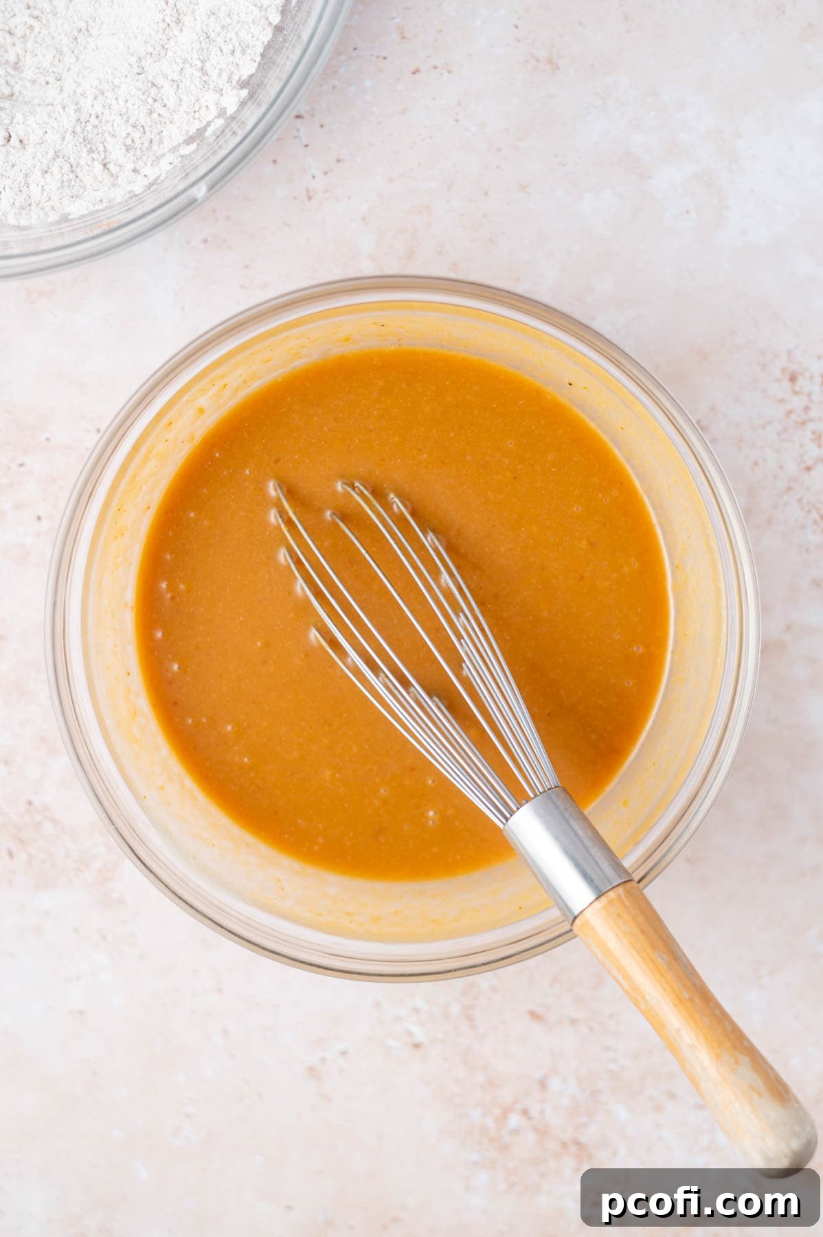 Pumpkin puree, milk, and vanilla extract are added to the whisked wet ingredients and mixed until smooth.