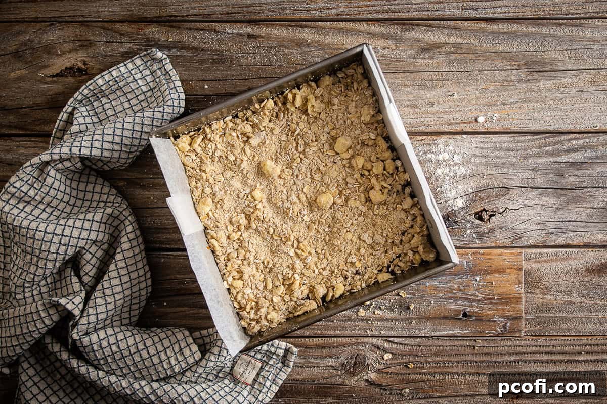 Final layer of crumb base added on top of the layers for Oatmeal Carmelitas.
