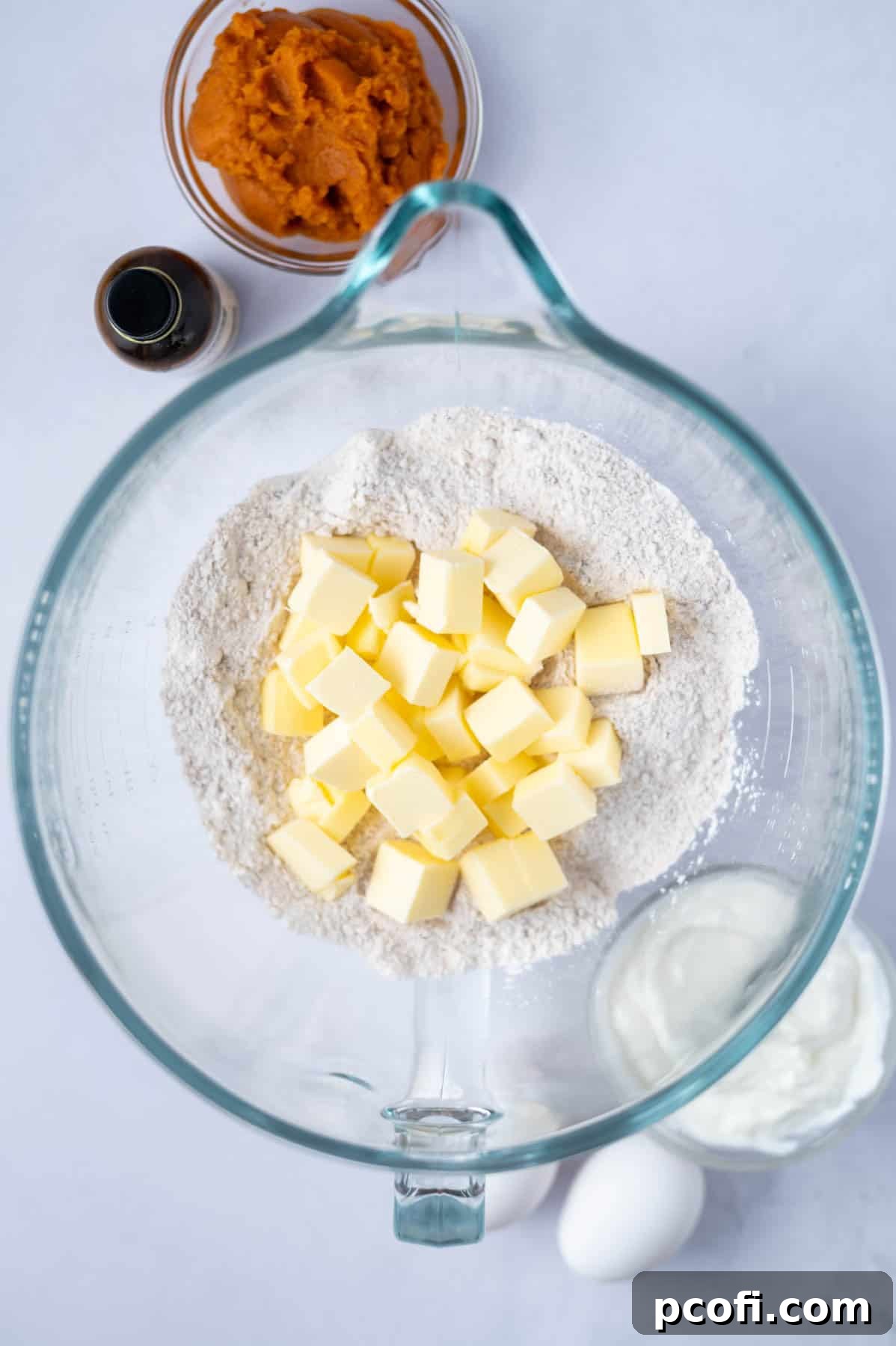 Cubed, softened butter being added to the dry ingredient mixture in a large mixing bowl, preparing for the reverse creaming method.