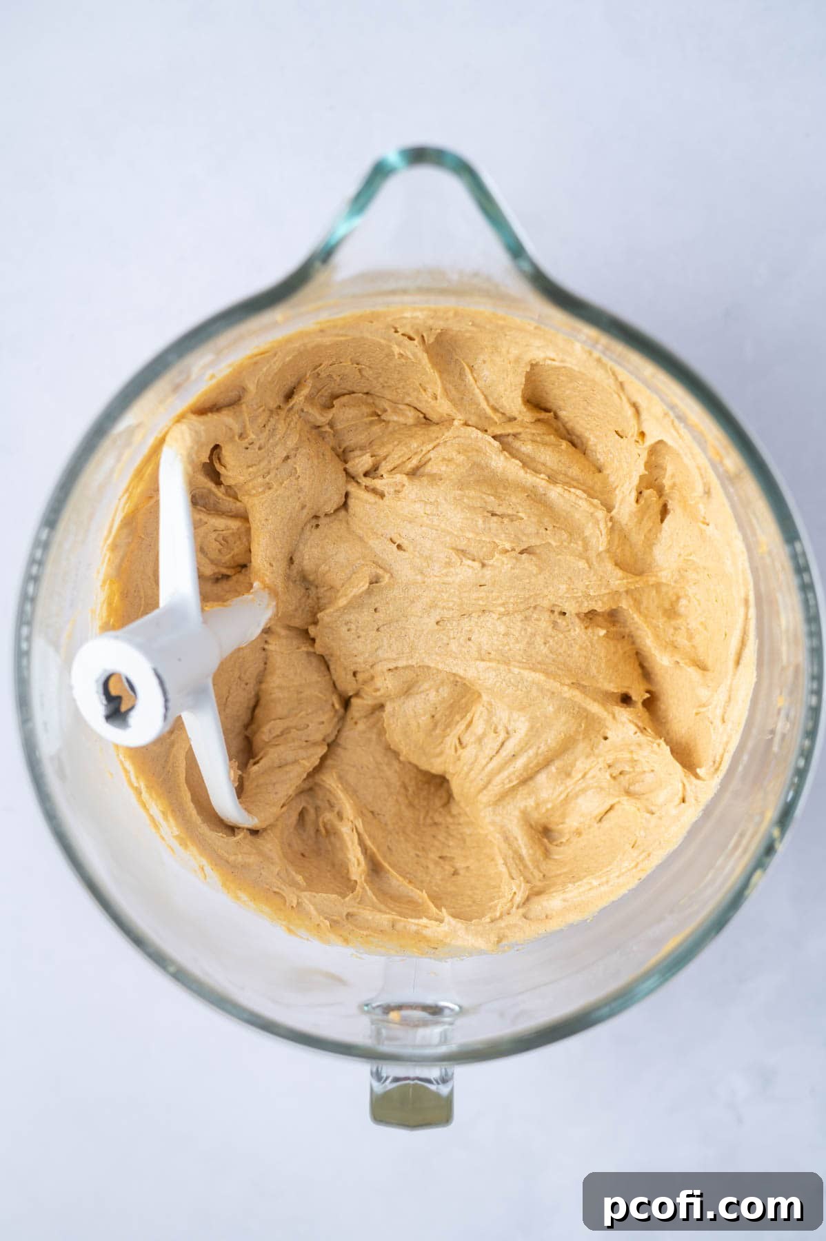Smooth, orange-hued pumpkin layer cake batter in a large mixing bowl, perfectly mixed and ready for baking.