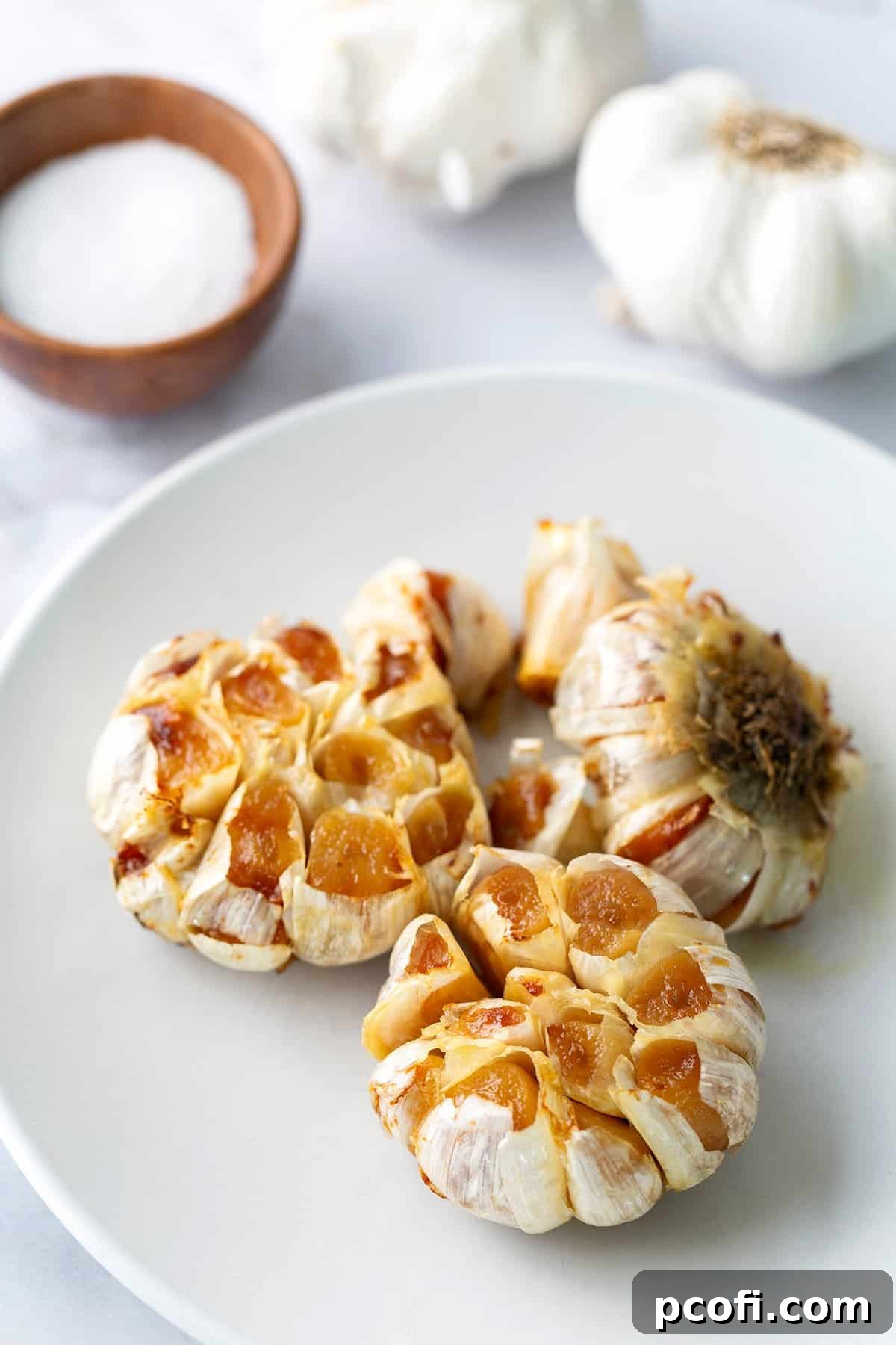 Roasted garlic heads on a plate, golden brown and soft.