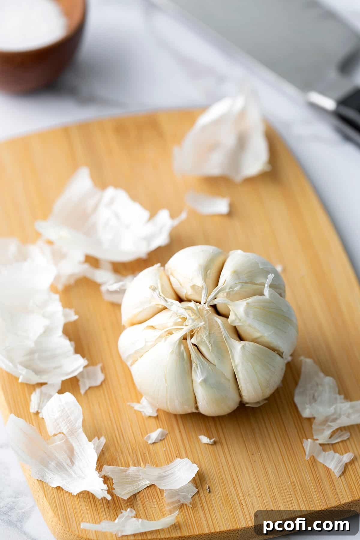 Garlic head with excess papery layers removed, exposing the cloves slightly.